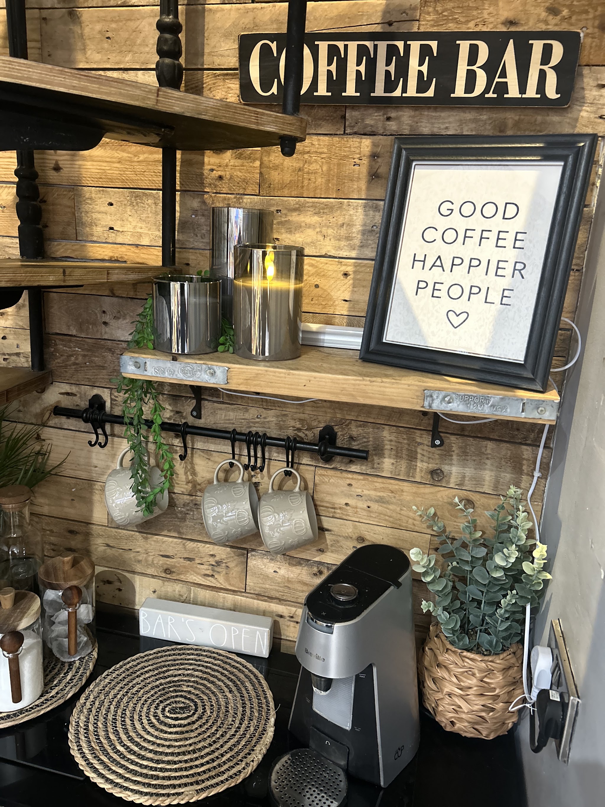 The coffee bar corner at The Nook, with a reclaimed wood wall and mugs on a rail